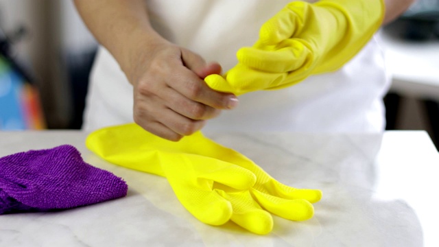 脱下黄色的工作手套，放在厨房柜台上完成家务视频下载