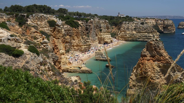 葡萄牙阿尔加维马里尼亚海滩的天然洞穴。在阿尔加维地区的葡萄牙海岸的马里尼亚海滩和绿松石海水上的岩石悬崖拱门。视频素材