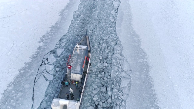 无人机追逐在结冰湖面上移动的一艘小型破冰船视频素材