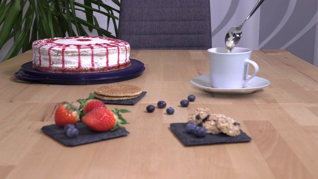看不见的鬼搅着咖啡，蛋糕和饼干立在桌子上视频下载