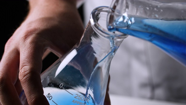 加州大学的科学家将蓝色液体倒入烧瓶中视频下载