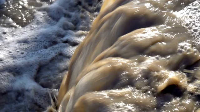 一股肮脏的褐色水流进河里。环境污染。的概念。特写镜头。4 k视频素材