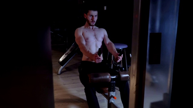 英俊的年轻人在健身房用划船机锻炼视频素材
