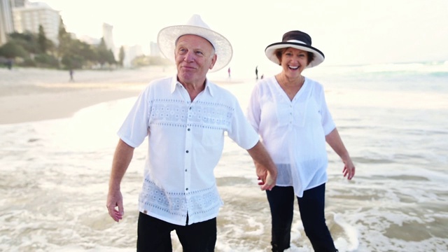 一对幸福的老年夫妇在海滩上散步视频下载