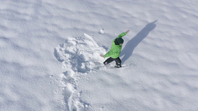 快乐的人害怕了，在冬天跑着走在白色的雪堆上。从无人机鸟瞰图上看到一个人坠落在雪堆上。顶部鸟瞰图人类脚印在白色蓬松的雪视频下载