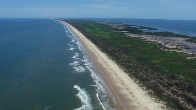 海浪撞击海滩的鸟瞰图在墨西哥海湾与Matagorda船舶海峡，德克萨斯州的远景。视频素材