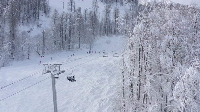 在山区度假胜地骑滑雪和滑雪板的人。鸟瞰图缆车移动的冬季度假村。无人机观看冬季运动和人们在雪坡上的活动视频下载