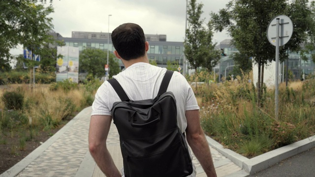 成年白人男子背着背包走在城市户外的街道上视频下载