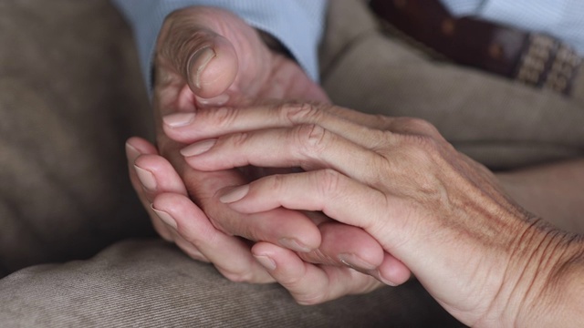 富有同情心的老夫妇互相抚摸着对方的手。视频素材