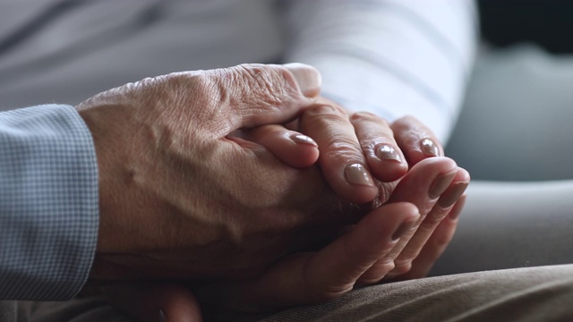 近距离观看一位老妇人握着退休丈夫布满皱纹的手。视频素材