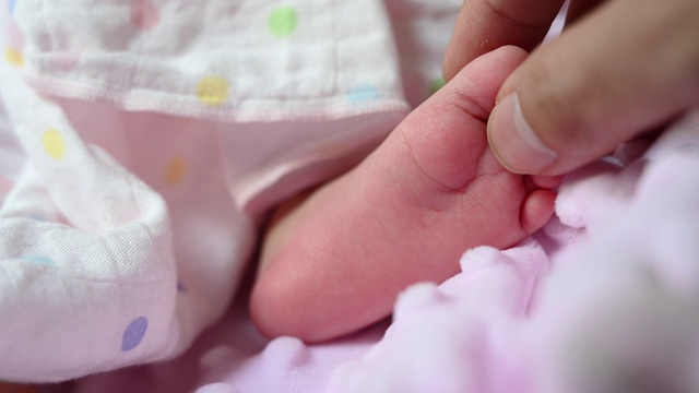 4K靠近亚洲母亲的脚和手和新生婴儿的抱和保护。母爱与婴儿和新生儿牵手的概念背景。视频素材