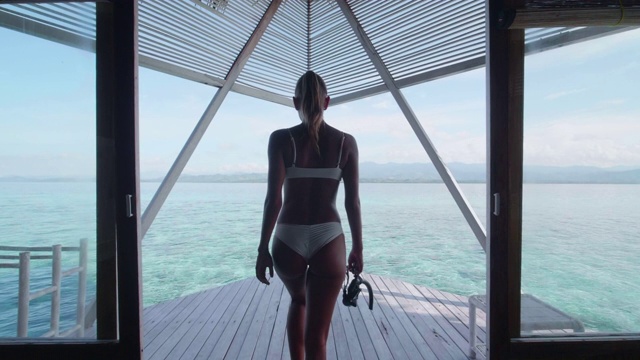 一个穿着比基尼的女人在度假的热带岛屿酒店度假村的对称场景。视频下载