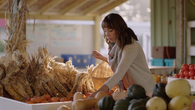 在秋天的农贸市场，一位妇女把小南瓜放进她的篮子里视频素材