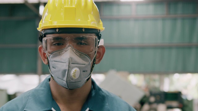 自信的年轻产业工人肖像，戴着面具，近距离。慢动作，亚裔男性，工作服，头盔。工业和制造业概念。视频下载