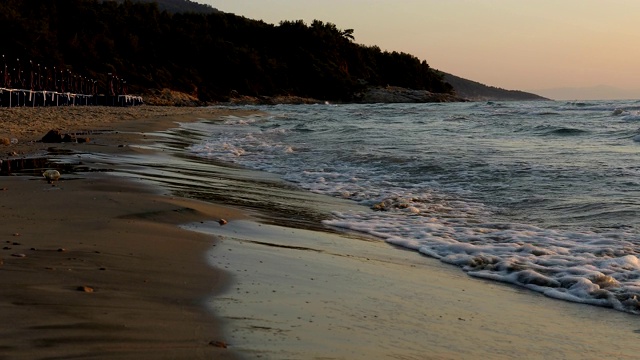 日出时，年轻女子在海滩上冲过海浪视频素材