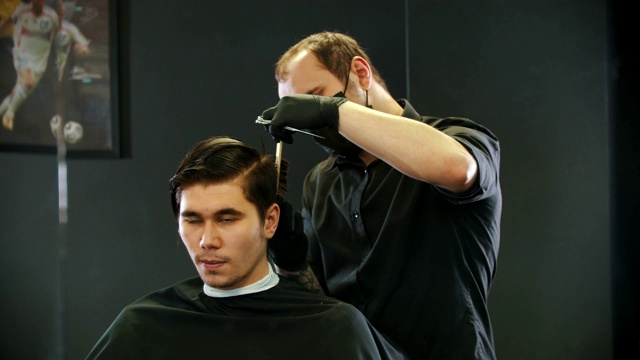理发师将年轻的顾客湿漉漉的头发剪在后照镜子上视频下载