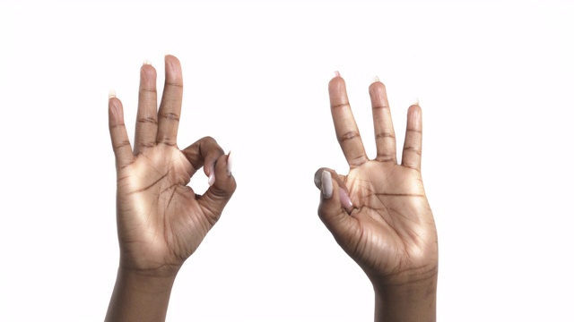 一名非洲妇女在白人背景下双手举ok手势。肢体语言的概念视频下载