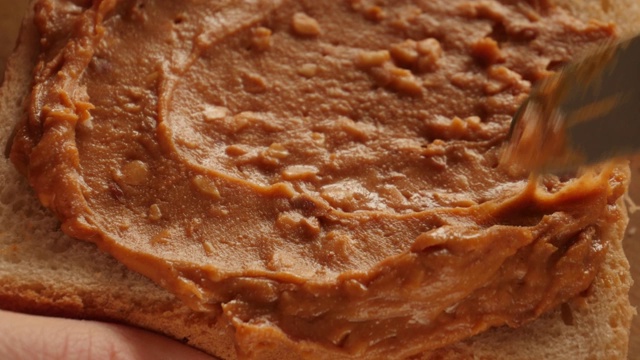 把花生酱涂在烤面包上，做三明治视频素材