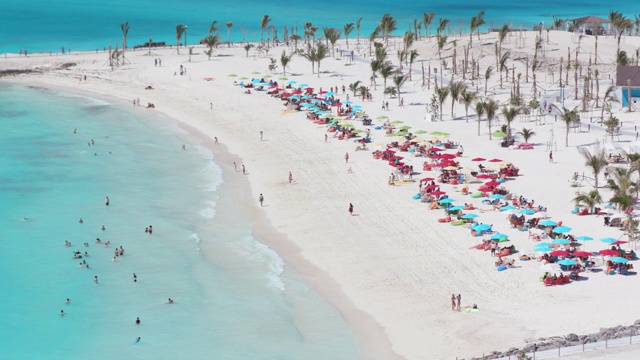 鸟瞰在拥挤的热带海滩游泳和晒日光浴的游客视频素材