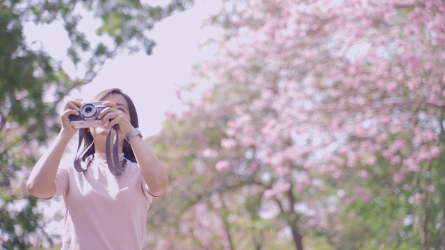 快乐的亚洲女游客在春花公园散步，在假日旅游中拍照休闲活动视频素材