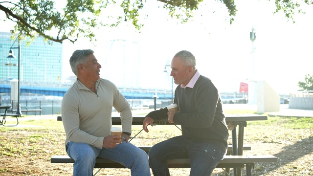 两个男人坐在公园里聊天，喝着咖啡视频下载