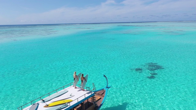 两名妇女与冲浪板在传统的马尔代夫船在海洋视频下载