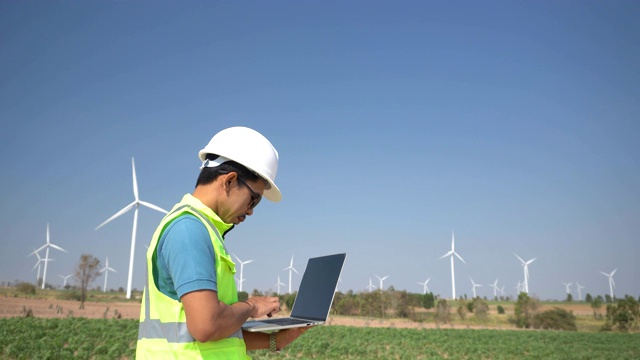 年轻工程师在风力涡轮机农场使用计算机视频素材