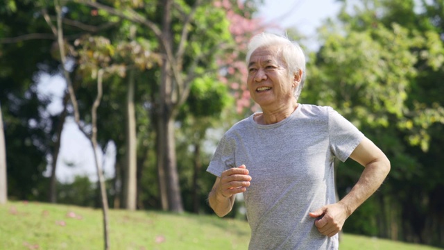 一位亚洲老人在公园慢跑视频素材