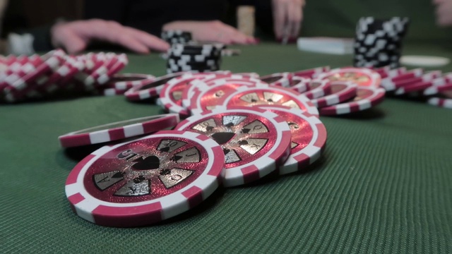 扑克筹码的特写在绿色的布上玩扑克的人的背景视频素材