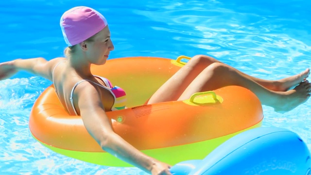 年轻女子在游泳池里玩一个浮胎视频下载