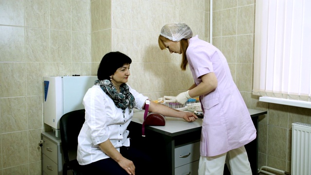 一名女性实验室助理从一名成年女性的静脉中抽取血液。高清视频下载