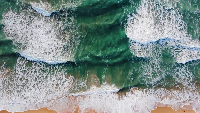 天堂海滩鸟瞰图从上到下拍摄，泡沫的海浪翻滚，来到沙滩上视频素材