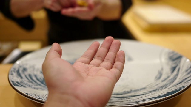 一位顾客在一家日本餐馆里从厨师那里拿寿司视频下载