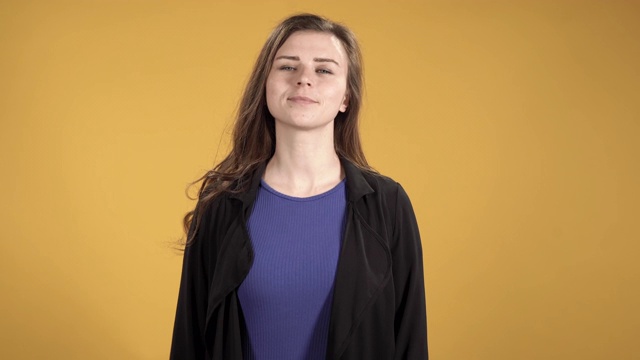 黄色背景下一个微笑的年轻女子的肖像视频素材