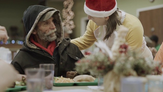 美国犹他州普罗沃，一名戴着圣诞帽的志愿者正在为无家可归者提供食物视频下载