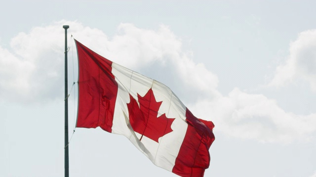 在一个阳光明媚的日子，加拿大国旗在风中飘扬的慢动作镜头视频素材