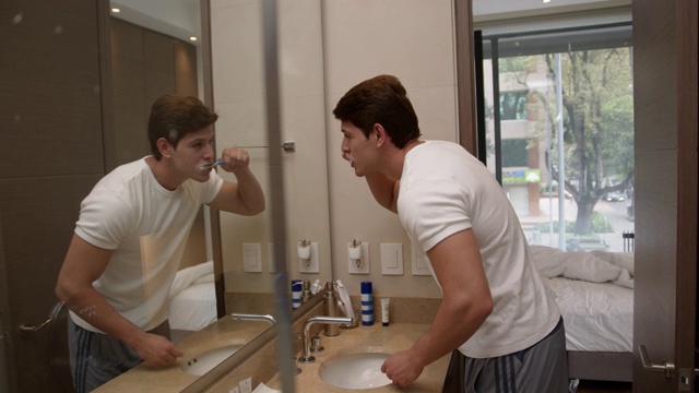 年轻人开始一天的生活，一边对着镜子一边刷牙视频素材
