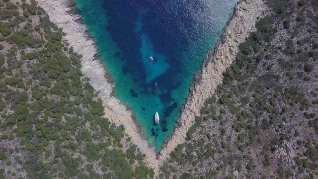 一艘帆船停泊在希腊斯基亚索斯的V形海湾的无人机图片。——延时视频下载