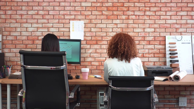 后视图亚洲商业女性和同事工作在他们的办公桌在办公室视频素材