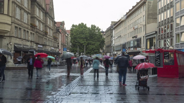 在德国慕尼黑，人们在雨天穿过卡尔斯特广场(Stachus)的卡尔斯特大门，但游客仍然带着雨伞观光视频下载