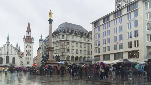 在慕尼黑的玛丽恩广场和慕尼黑市政厅下着雨，德国游客仍带着雨伞观光视频下载