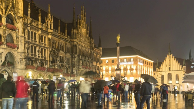 在慕尼黑的玛丽恩广场和市政厅白天下雨晚上，德国游客仍带着雨伞观光视频下载