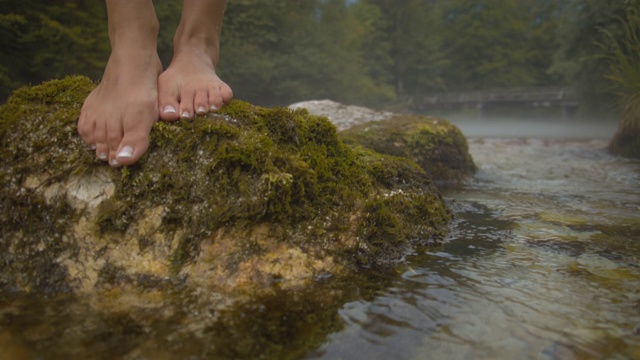 一个女人的脚踩在河里的石头上视频下载