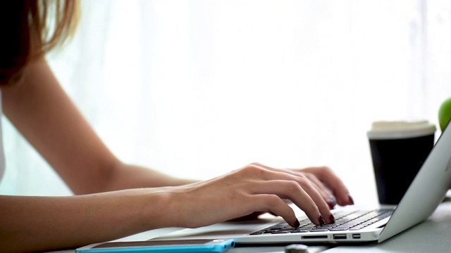 一个年轻的商务女性在键盘上打字。在公司办公室用键盘打字的女秘书向主管老板提交总结报告。视频素材