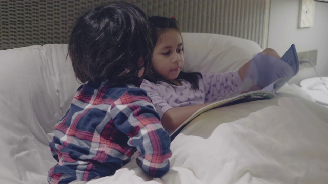 姐姐在他们的公寓里给小男孩读童话故事视频素材