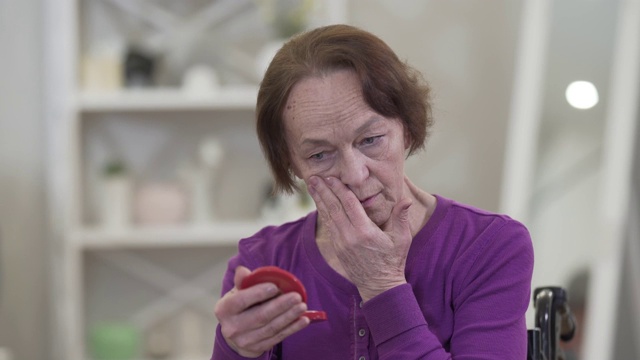 画像沮丧的老白人妇女看着手镜与阴沉的面部表情。年老的退休女性怀念逝去的美丽。视频素材