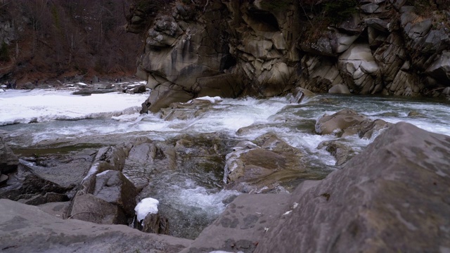 在冬天从山溪和石滩中急速流动的水和雪。瀑布。慢动作视频素材