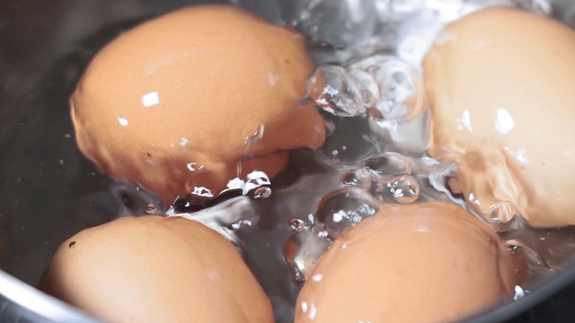 鸡蛋在不锈钢锅里煮，特写。沸腾的水视频素材