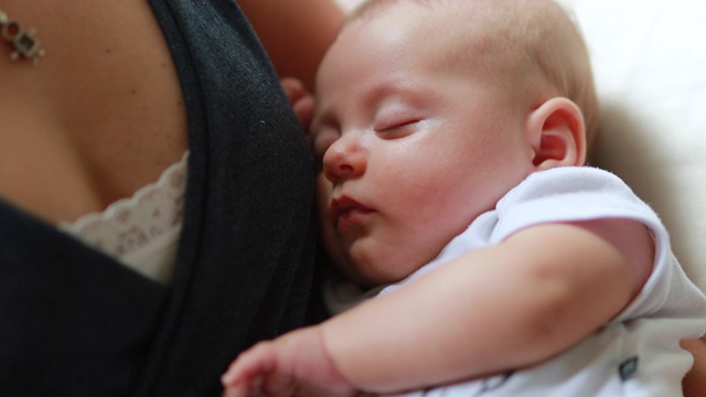 刚出生的婴儿闭着眼睛睡在妈妈的怀里视频素材
