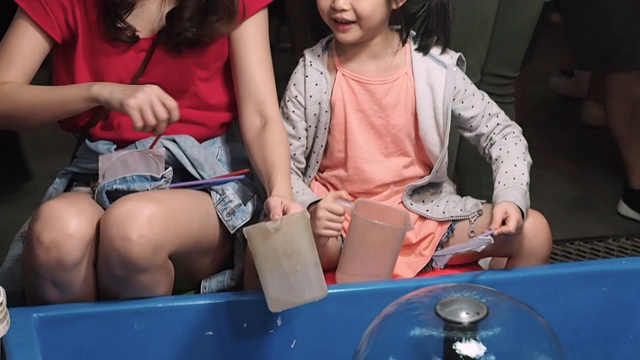 妈妈和女儿玩游戏，拿纸抓鱼在水里视频素材